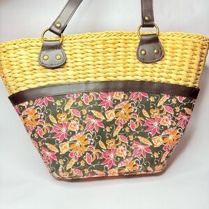 Straw tote bag with floral print, featuring brown leather trim and straps: